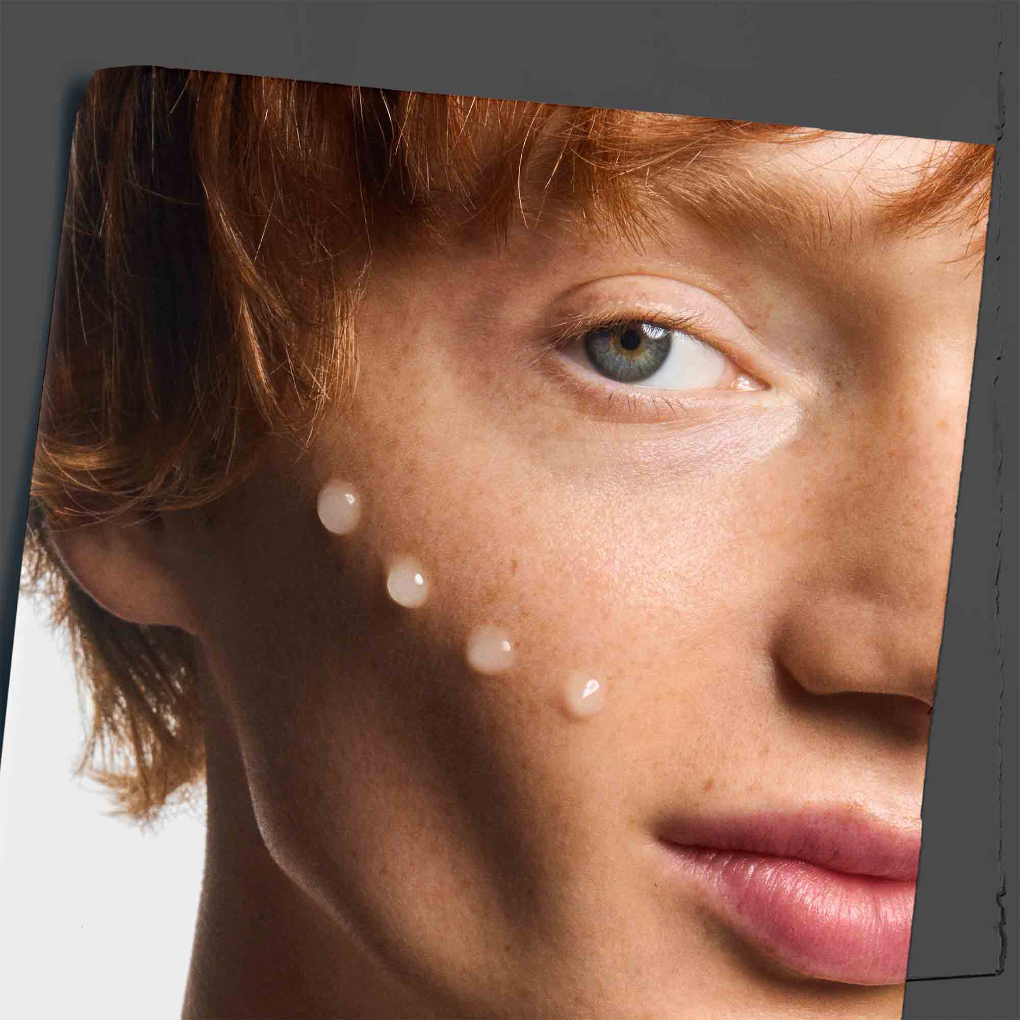 Age Defender Power Serum applied to a cheekbone, demonstrating its use on skin.