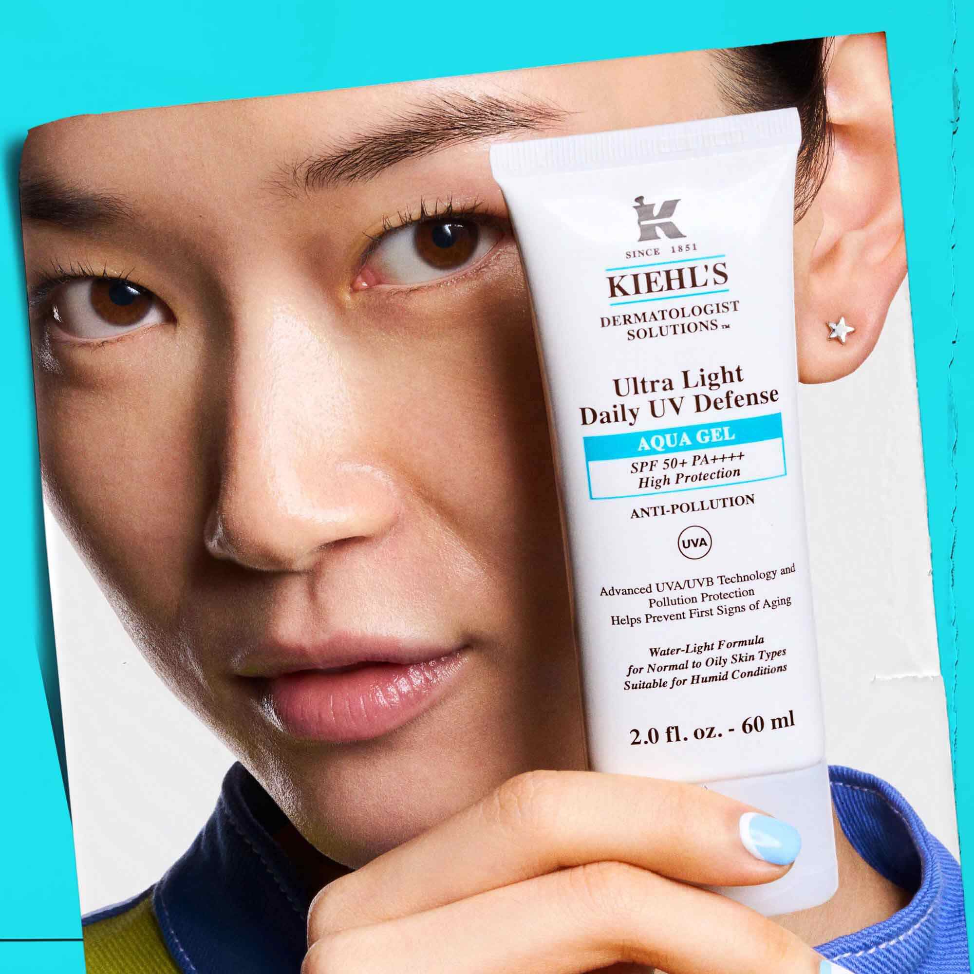 A model holding a tube of Ultra Light Daily UV Defense Aqua Gel, showcasing its portability and ease of use.