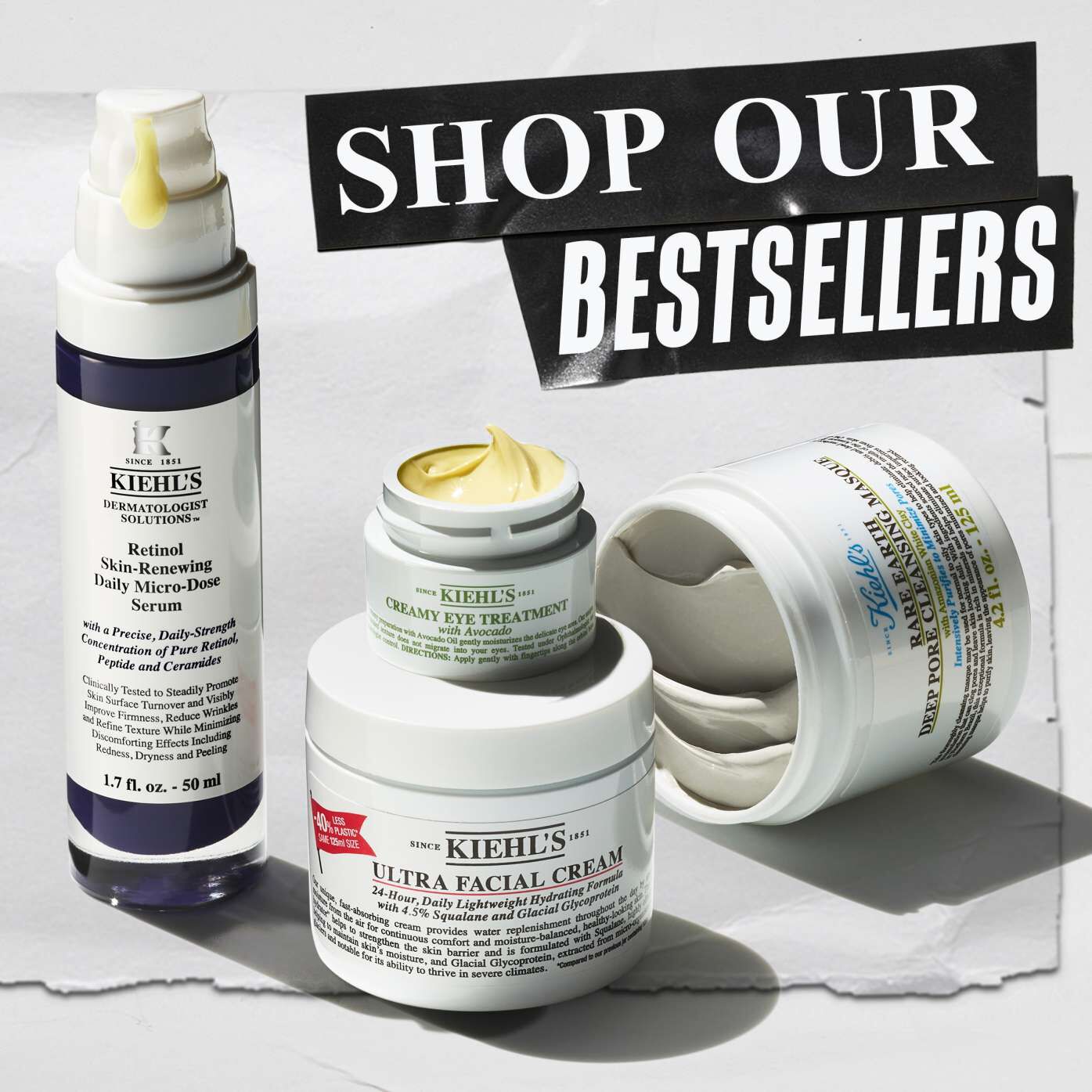 Kiehl's bestseller products are displayed, including a serum, eye treatment, facial cream, and clay mask set against a textured background, with bold text reading "Shop Our Bestsellers."