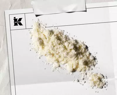 A pile of white powder on a blank sheet of paper with a logo in the corner, suggesting an artistic or stylistic presentation.