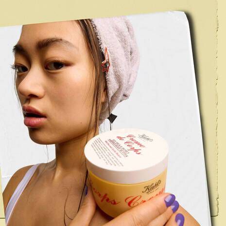 A woman holds a tub of Kiehl’s Creme De Corps Body Butter to her shoulder. 