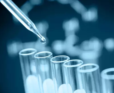 A close-up of a dropper releasing a liquid into a series of test tubes, set against a blue background with a molecular structure design.