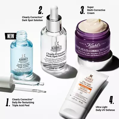 Alt text: A product display featuring four Kiehl's skincare items, including Clearly Corrective Dark Spot Solution, Super Multi-Corrective Cream, Clearly Corrective Triple Acid Peel, and Ultra Light Daily UV Defense, arranged on a white background.