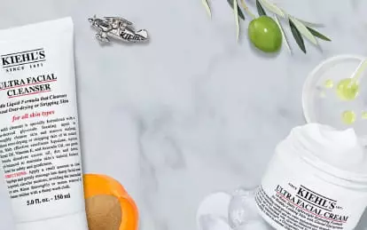 Product display featuring Kiehl's Ultra Facial Cleanser, Toner, and Cream on a marble background, along with citrus fruits and skincare accessories.