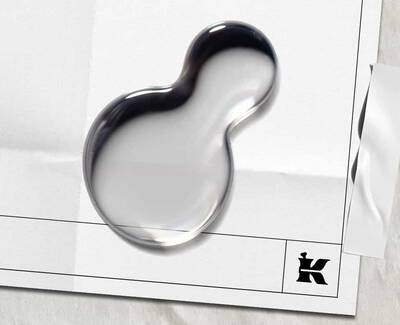 A shiny, abstract blob rests on white paper, featuring creases and a black 'K' logo in the bottom corner, creating a modern, artistic look.​