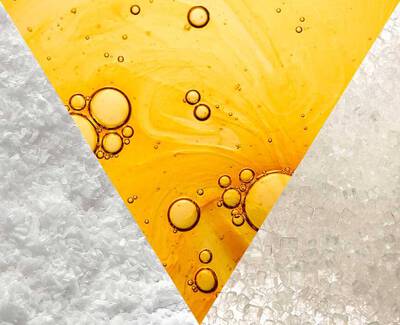 Triangular composition featuring textures of salt, a golden liquid with bubbles, and crystalline white sugar, creating a visually striking contrast.