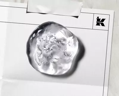 Close-up of a clear, textured skincare gel droplet on a laboratory document, featuring Kiehl’s iconic "K" logo, illustrating the brand's clinical approach to formula development. ​