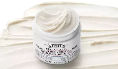 A jar of Kiehl's Ultra Facial Overnight Rehydrating Mask with a creamy texture, placed on a smooth, white background that resembles the product inside.