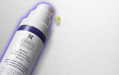 A flat lay of Kiehl's skincare products, including a cream, a serum, and a sunscreen, arranged on a brushed silver background.