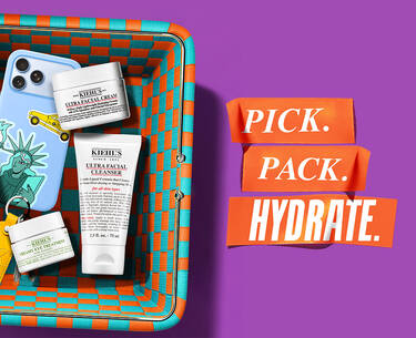Purple banner with a colorful woven basket containing travel-sized Kiehl's products: Ultra Facial Cream, Cleanser, and Avocado Eye Treatment. Text reads "BANK HOLIDAY PREP? SORTED. 3 FOR 2 ON TRAVEL MINIS*."