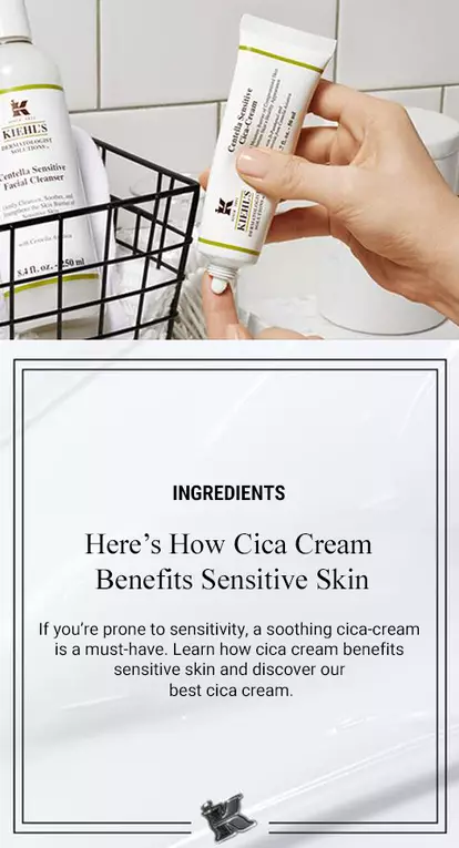 A clean bathroom setting featuring Kiehl's Cica Cream and a gentle facial cleanser. A hand holds the Cica Cream tube, and a wire basket displays the cleanser, emphasizing skincare for sensitive skin.