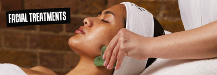 A woman receiving a facial treatment, with a gentle hand applying a tool to her face, in a serene spa setting. The words "FACIAL TREATMENTS" are prominently displayed in the image.