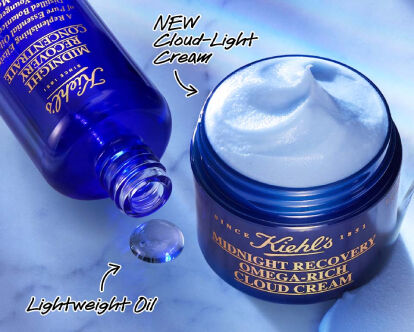 A jar of Kiehl's Midnight Recovery Omega-Rich Cloud Cream is shown with a small scoop taken out, beside a bottle of lightweight oil. The text promotes restoring younger-looking skin overnight and encourages customers to shop.
