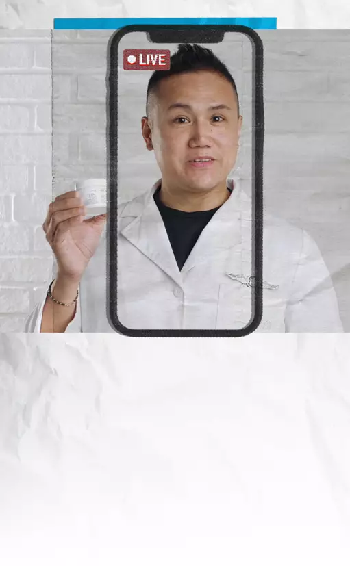 A man in a white lab coat holds a skincare product while appearing on a smartphone screen with a "LIVE" indicator at the top. The background features a textured white wall.